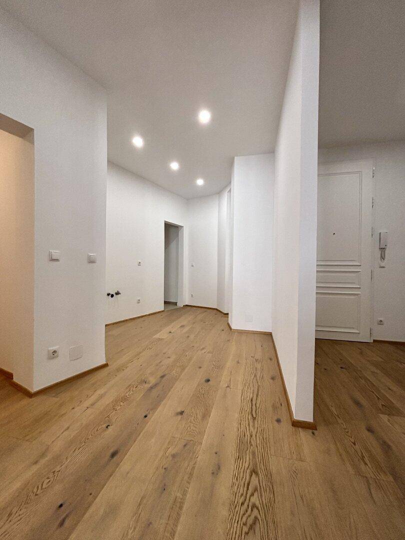 Langer, heller Flur mit Holzboden und Einbaustrahlern, der zu weiteren Räumen führt.