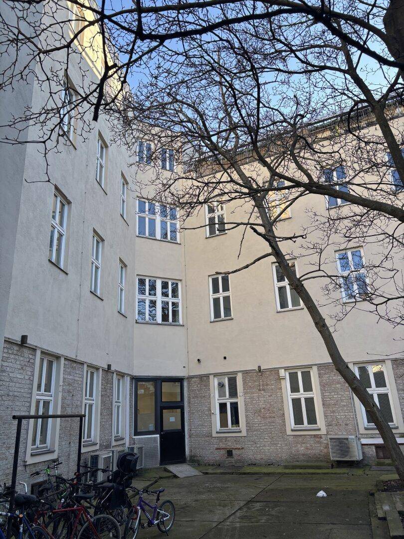Gebäudefassade eines Altbaus mit vielen Fenstern und Fahrrädern im Innenhof.