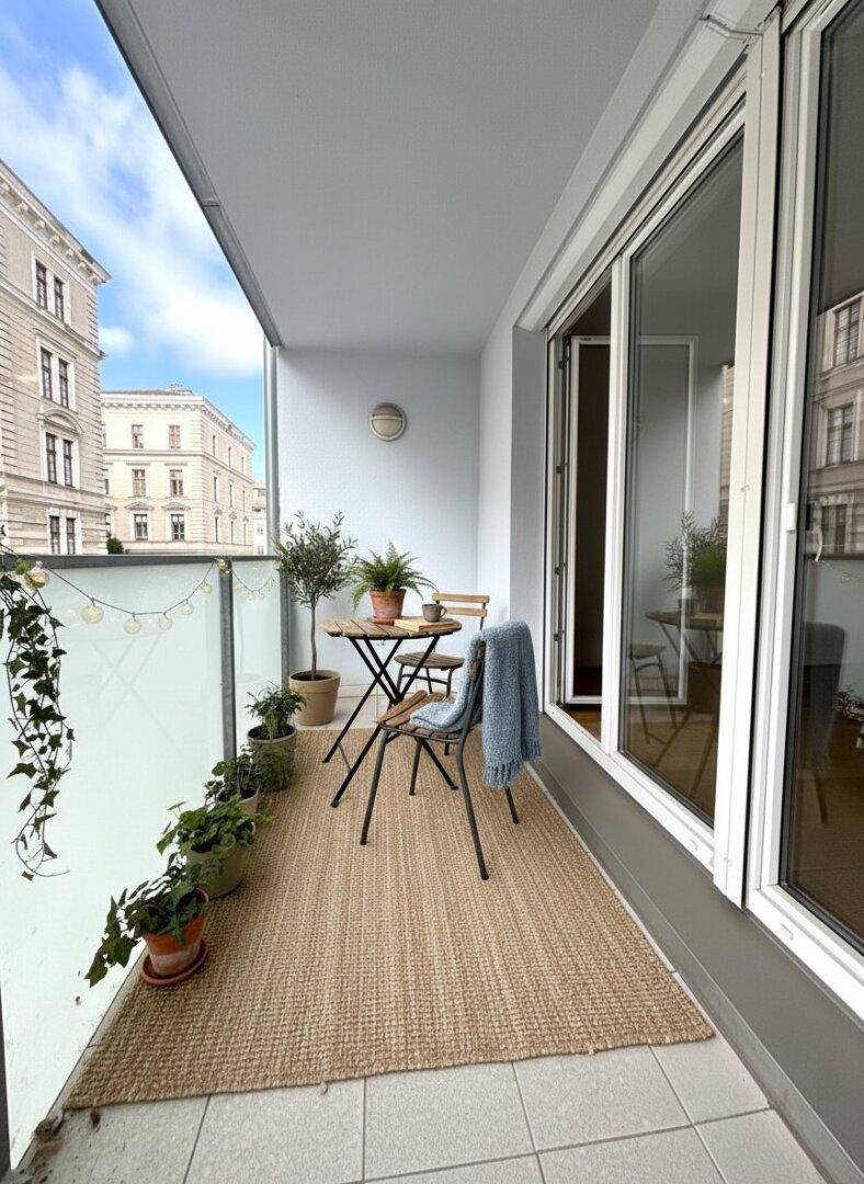 Möblierter Balkon mit Pflanzen und Blick auf die Stadtgebäude.