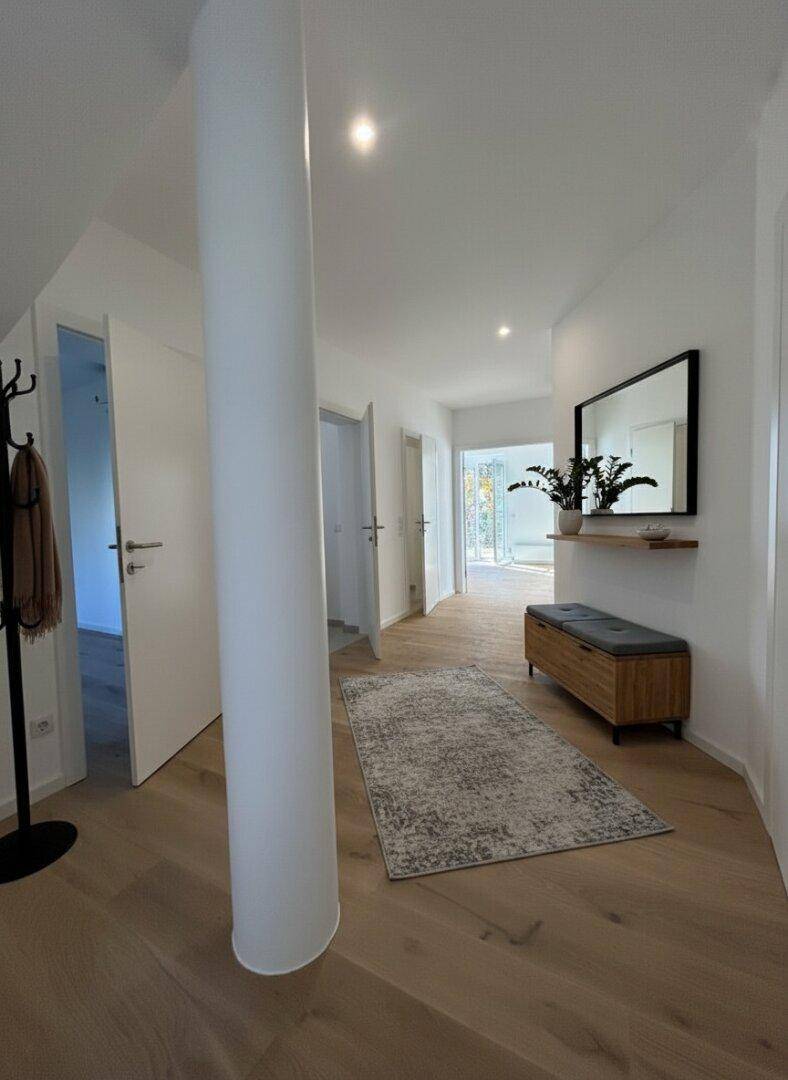 Heller Flur mit Holzboden, moderner Einrichtung und Zugang zu weiteren Räumen.