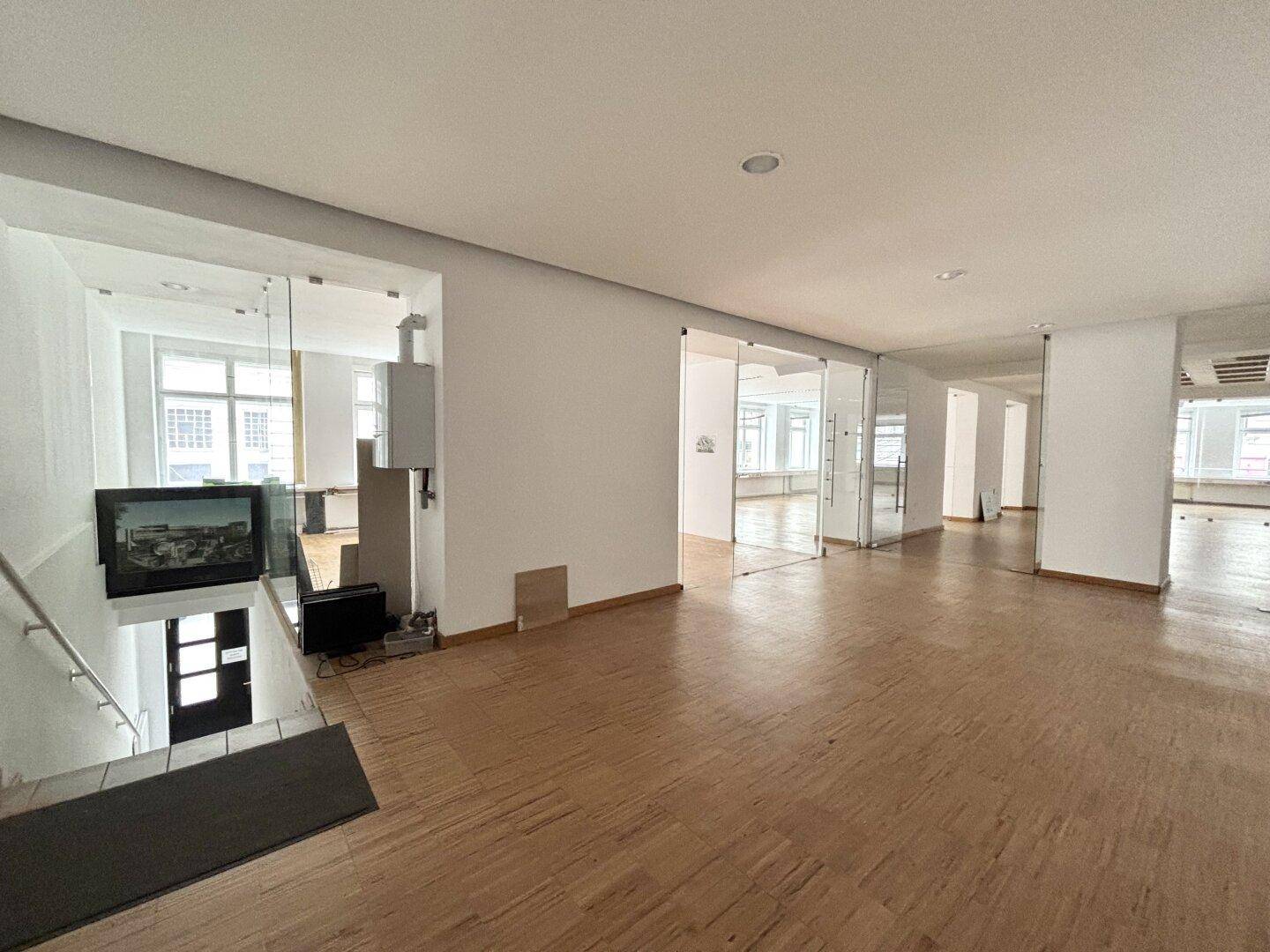 Büroraum mit Treppenabgang und weiteren Glasabtrennungen, die eine flexible Raumnutzung ermöglichen.