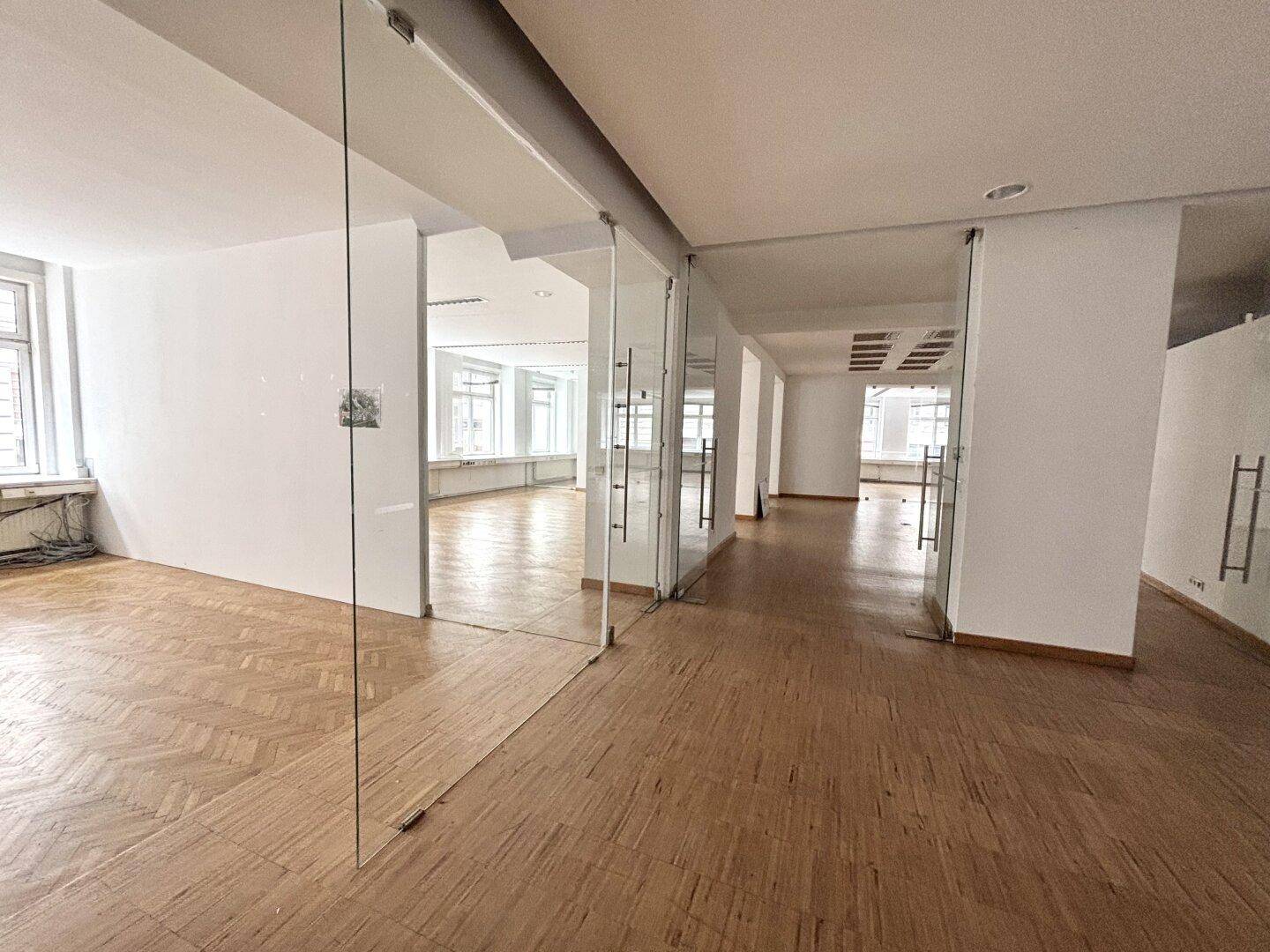 Großzügiger Bürobereich mit vielen Glaswänden und Türen, die für Transparenz und Helligkeit sorgen.