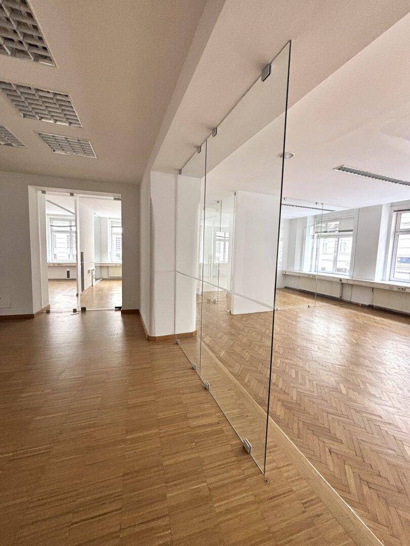 Moderner Bürobereich mit langer Glaswand, die den Raum strukturiert und für Helligkeit sorgt.