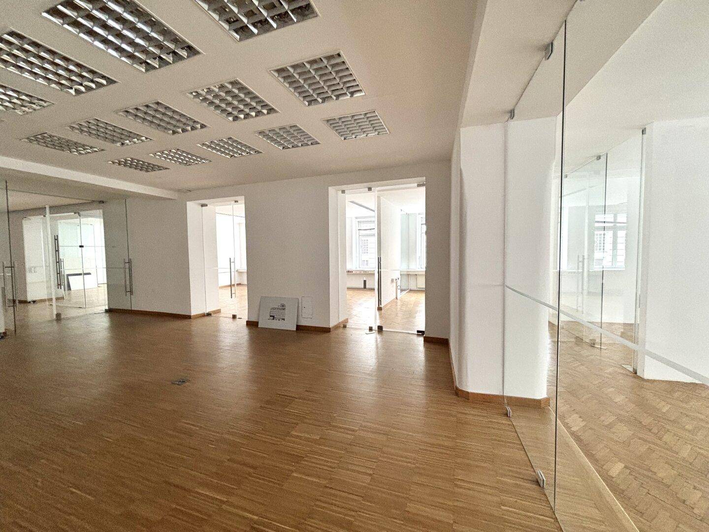 Großzügiger Bürobereich mit mehreren Glasabtrennungen und Deckenleuchten für eine flexible Nutzung.