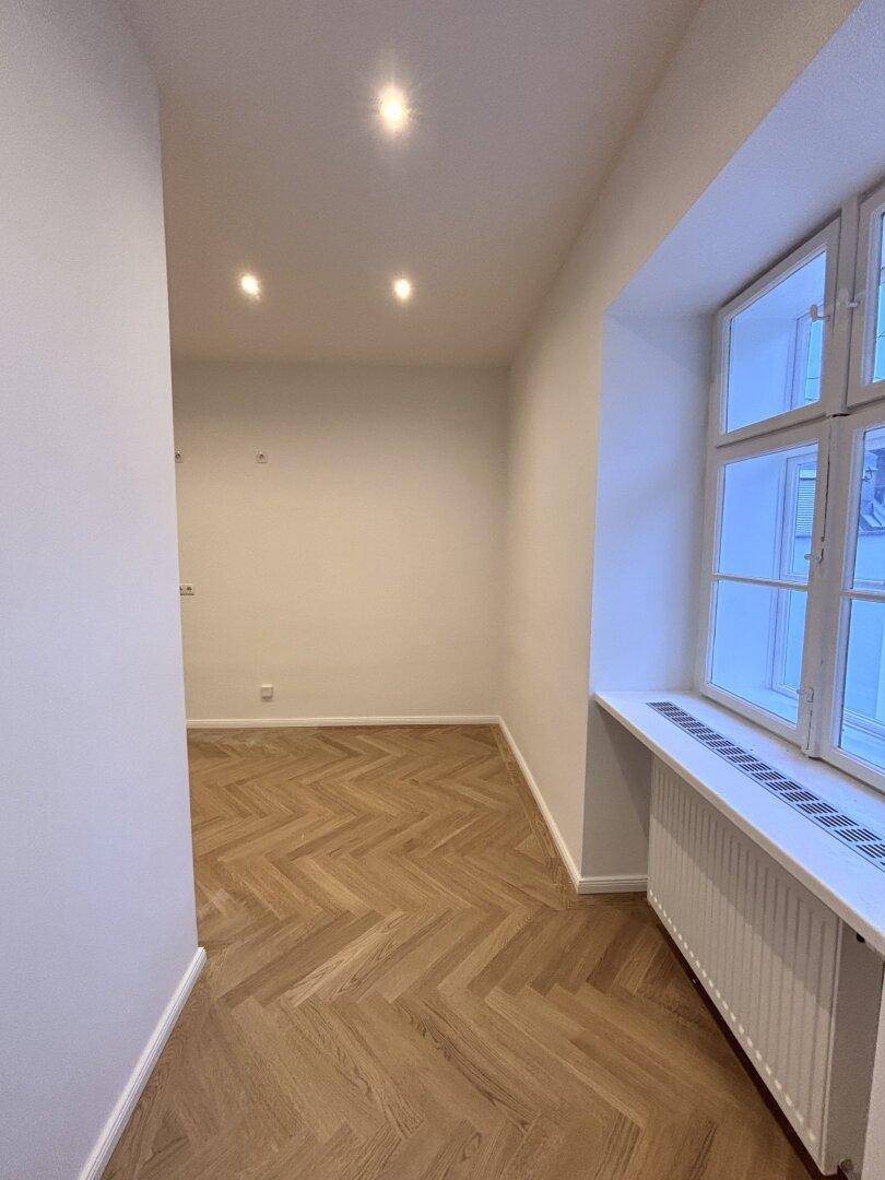 Langer, heller Flur mit Fischgrätparkett und Einbaustrahlern.