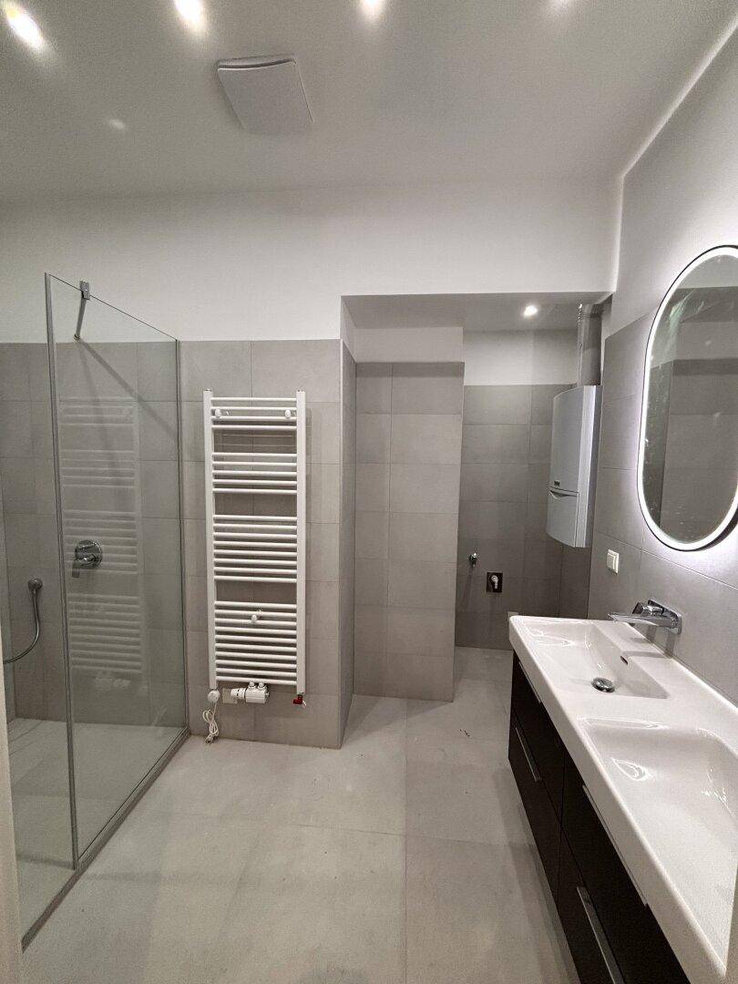 Modernes Badezimmer mit Doppelwaschbecken, begehbarer Dusche und Handtuchheizkörper.