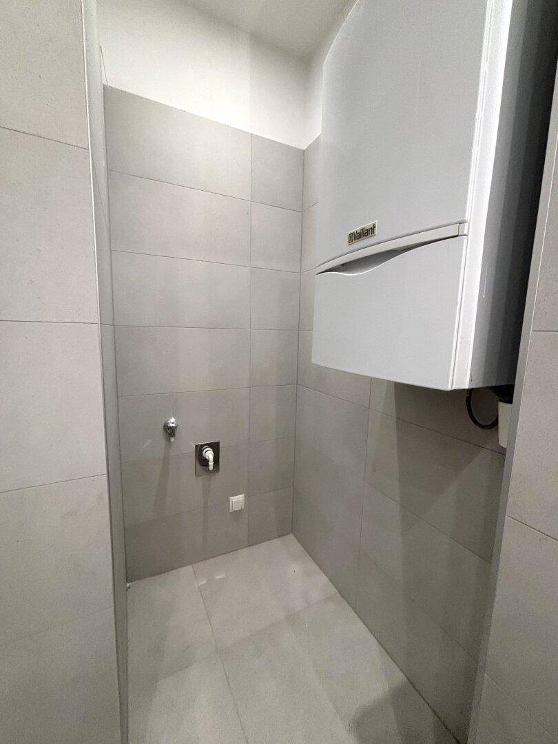 Kleiner Raum mit Heiztherme und Anschlüssen, ideal als Hauswirtschaftsraum.