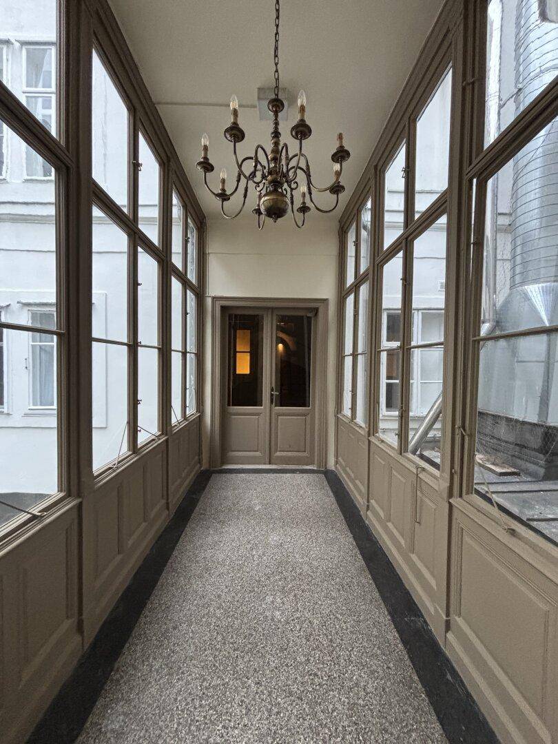 Verglaste Loggia mit klassischem Kronleuchter und Blick auf die umliegenden Gebäude.