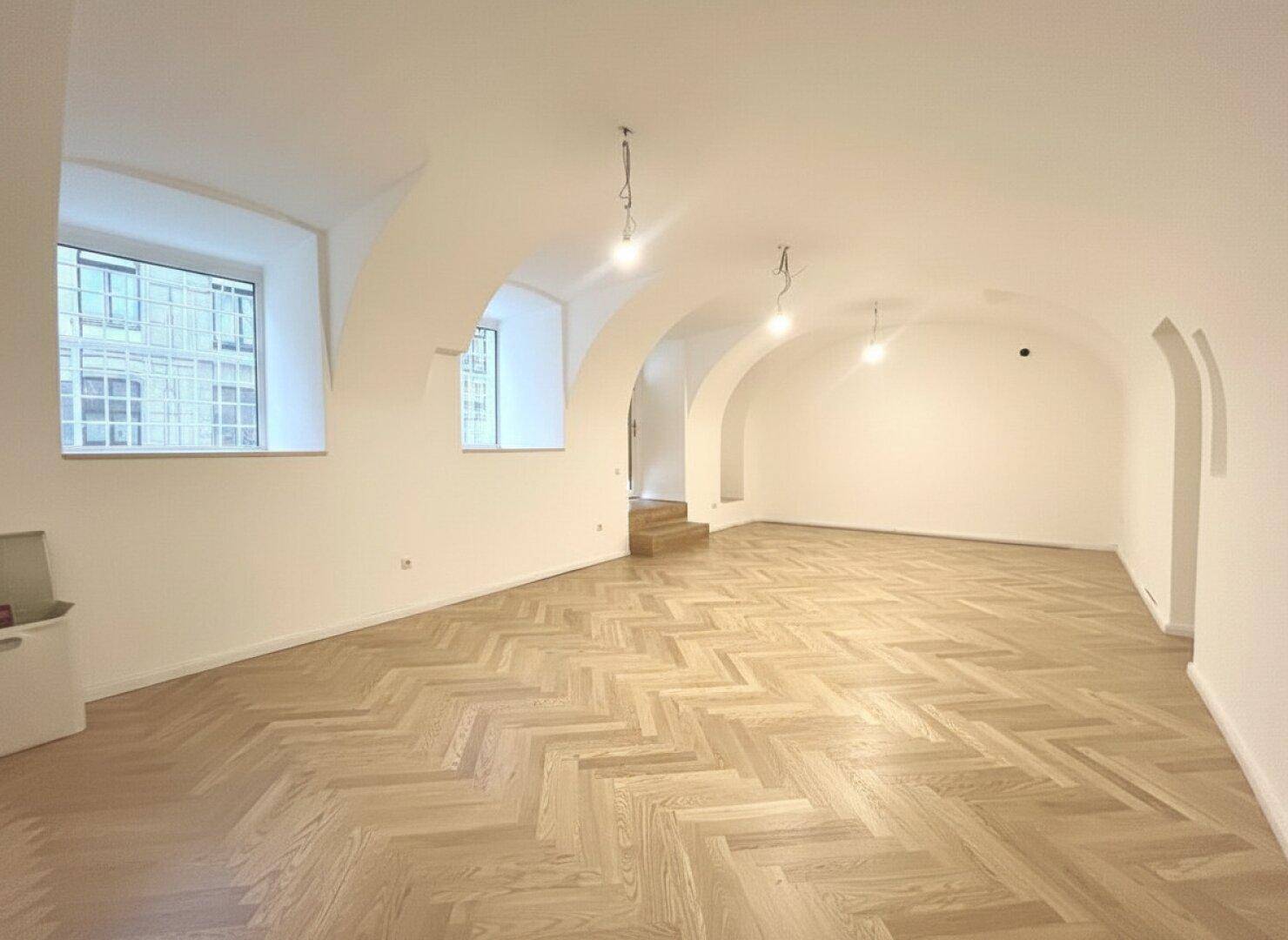 Heller, weitläufiger Raum mit hohen Gewölbedecken und klassischem Fischgrätparkettboden.