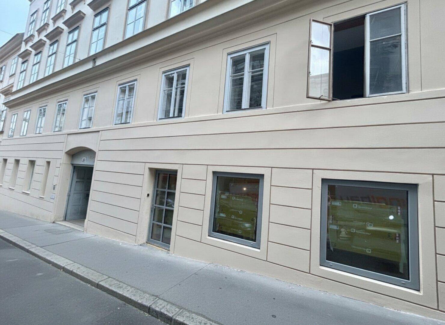 Klassische Gebäudefassade mit großen Fenstern und einem Eingangsbereich an der Straße.