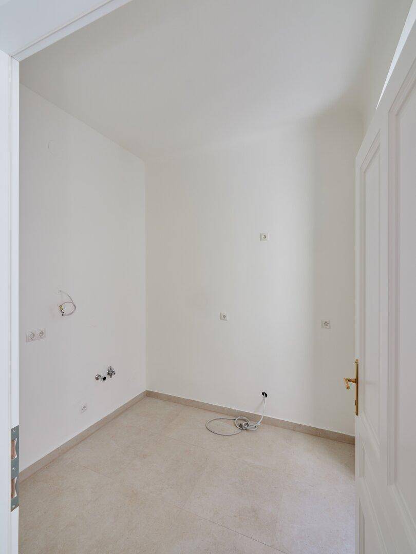 Kleiner Raum mit Fliesenboden, vorbereiteten Anschlüssen und einem Fenster, ideal für eine Küche oder Bad.