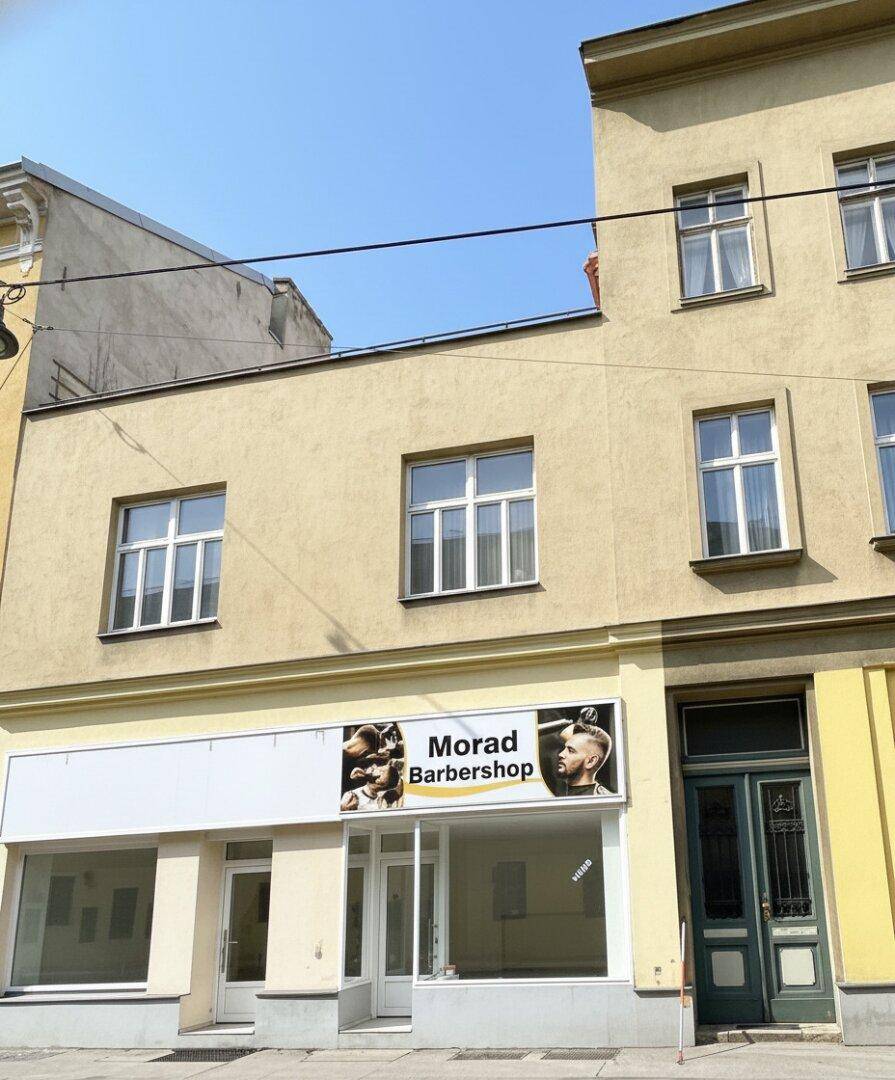 Fassade eines Gebäudes mit Geschäftsräumen im Erdgeschoss und Wohnungen darüber.