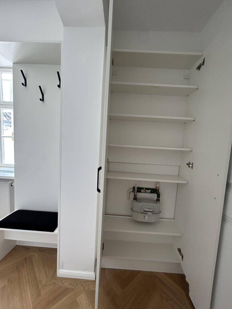 Heller Flur mit Einbauschrank, der einen Gaszähler beherbergt.