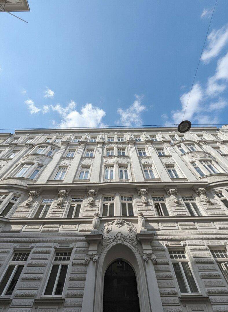 Prachtvolle historische Fassade eines Altbaus mit reich verzierten Details und hohen Fenstern.