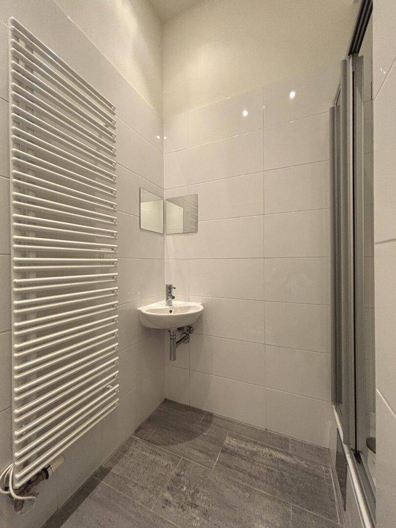 Modernes Badezimmer mit Dusche, Handwaschbecken und beheiztem Handtuchhalter.