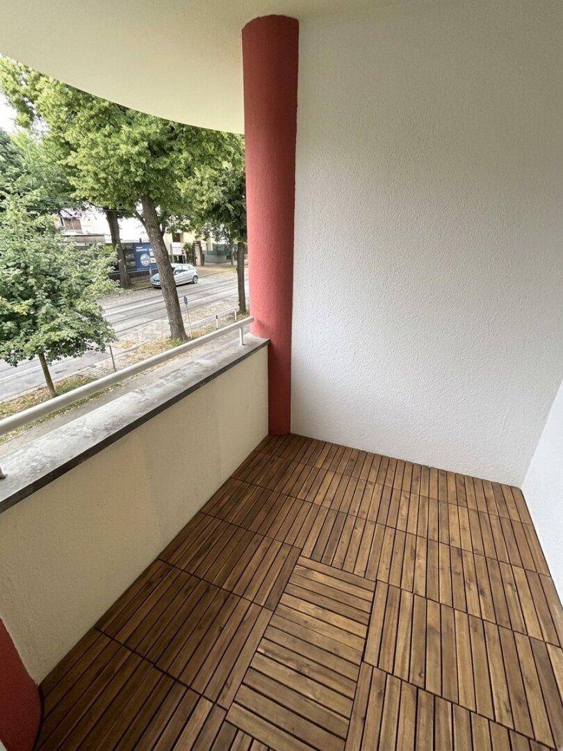 Balkon mit Holzbodenfliesen und Blick auf die belebte Straße.