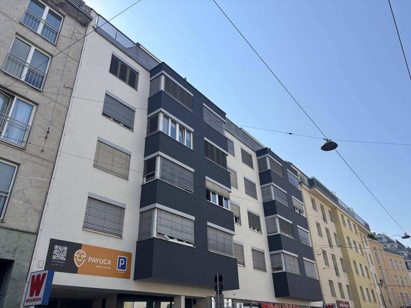 Moderne Gebäudefassade mit dunklen und hellen Elementen sowie vielen Fenstern.