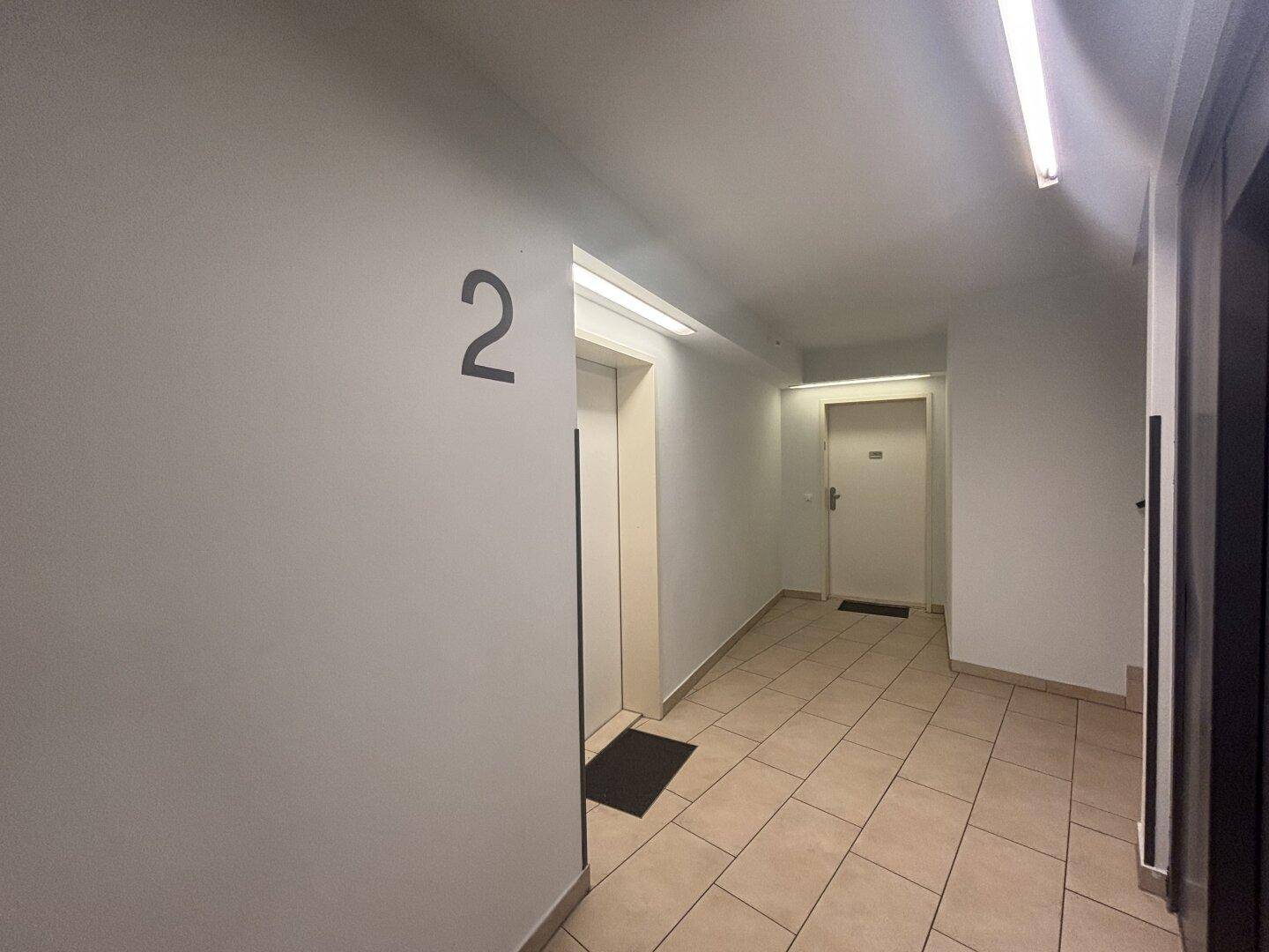 Heller Flur im Gebäude mit Aufzug und Zugang zu den Wohneinheiten.