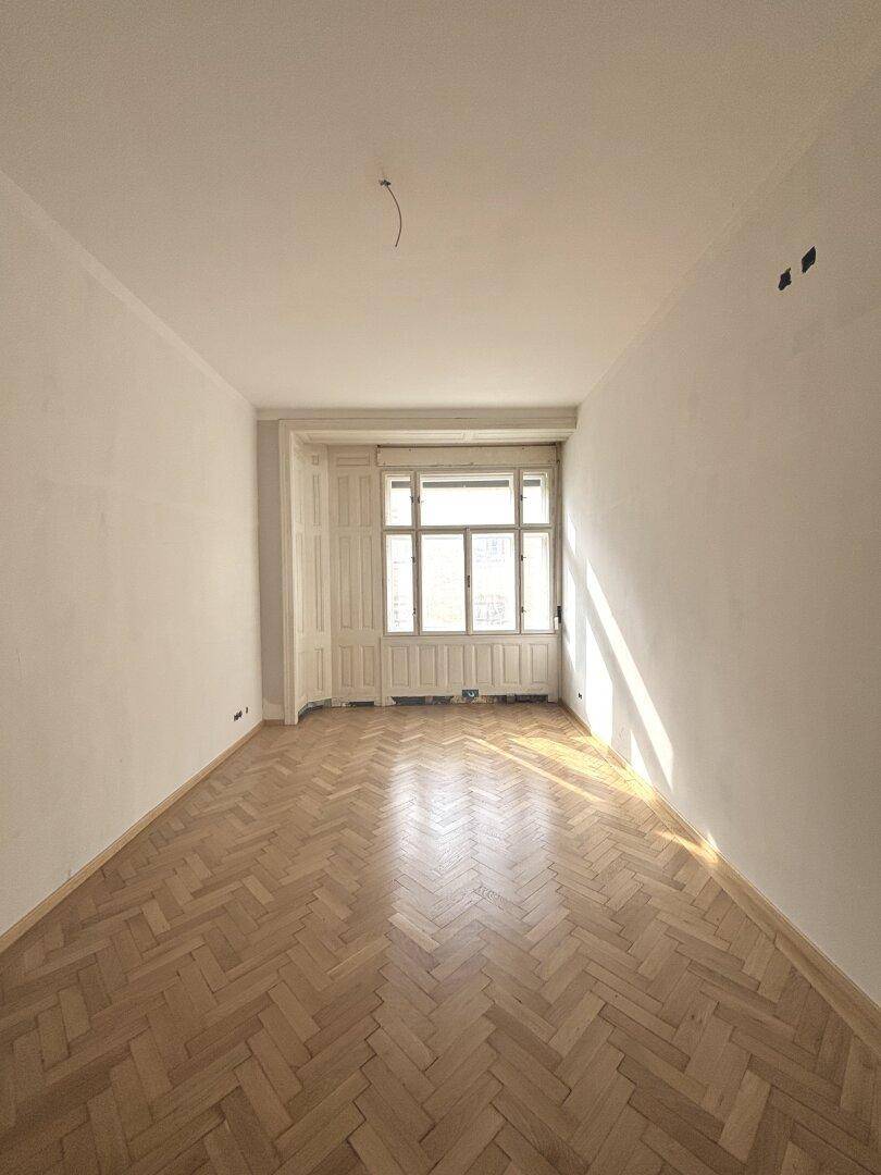 Heller Raum mit Fischgrätparkett und großen Fenstern, ideal für individuelle Einrichtung.