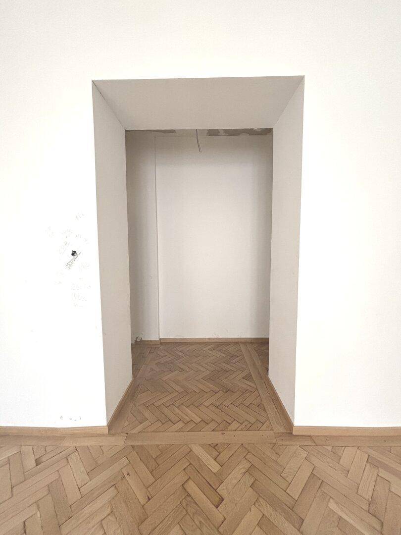 Türrahmen in einem Flur mit Fischgrätparkett, bereit für die Fertigstellung des Raumes.