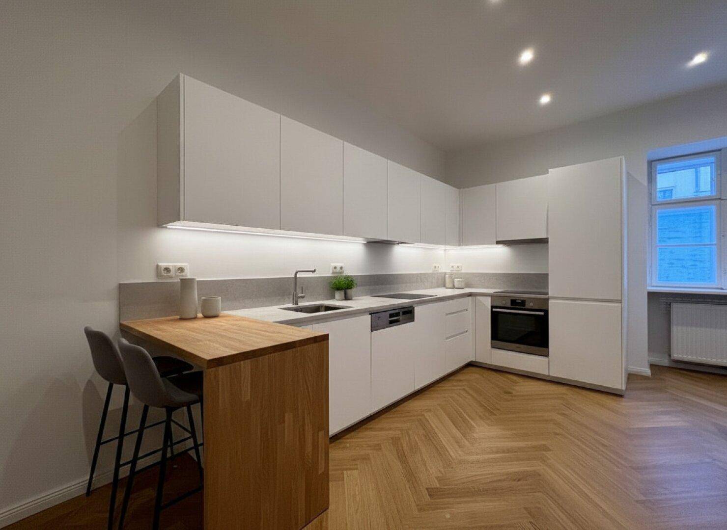 Moderne weiße Küche mit integrierten Geräten, Holztheke und Fischgrätparkett.
