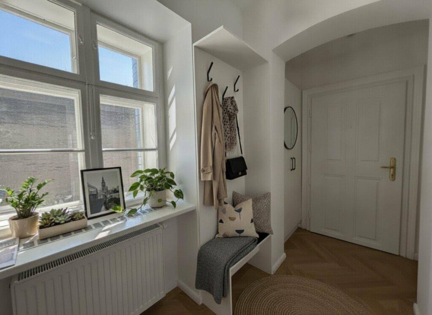 Heller Eingangsbereich mit Fenster, integrierter Sitzbank und Garderobenhaken.