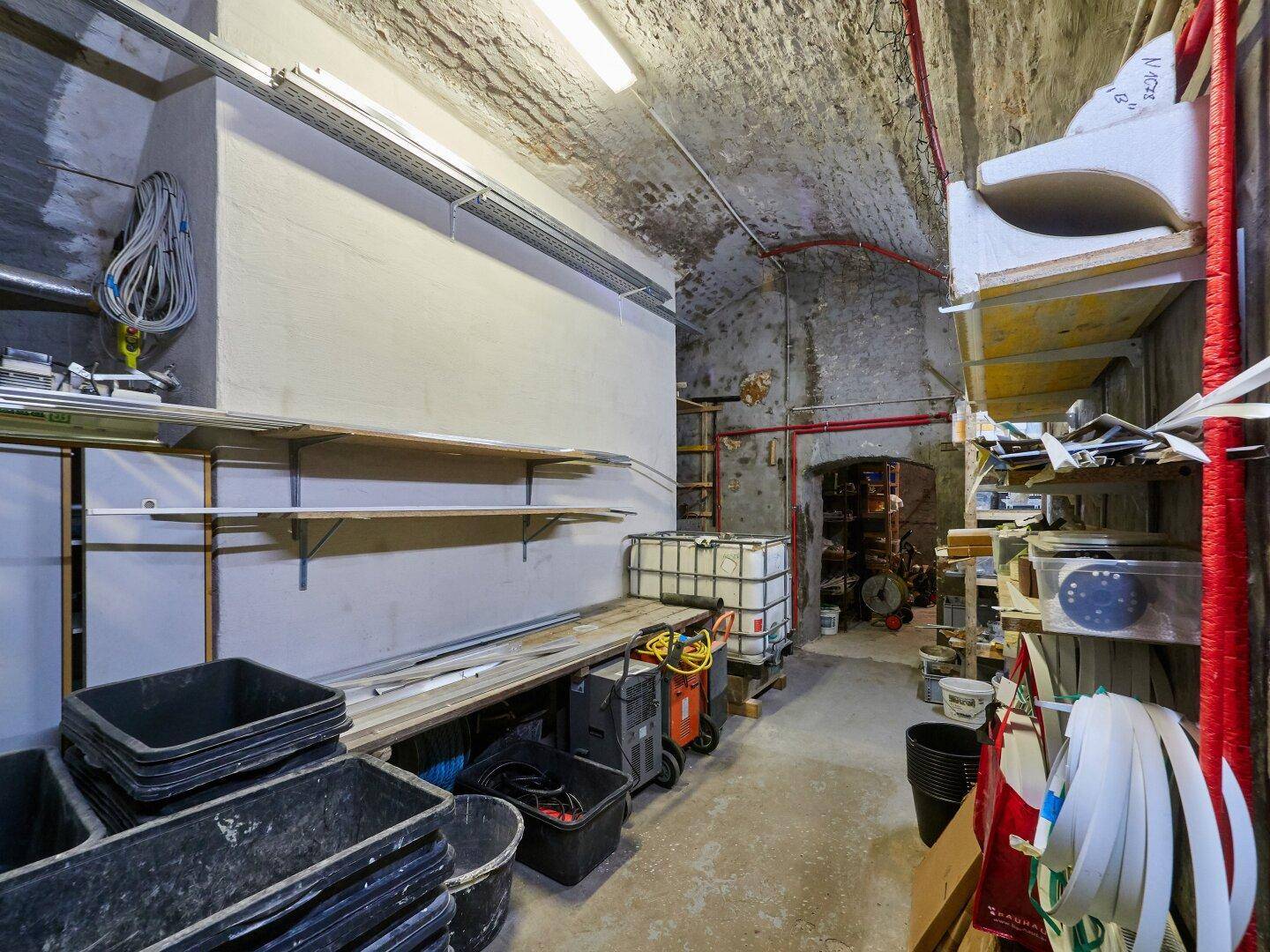 Geräumiger Lagerraum im Keller mit gewölbter Decke und Regalen für diverse Materialien.