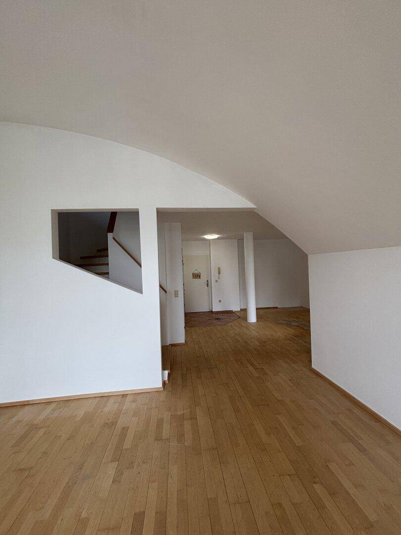 Heller Eingangsbereich mit Holzfußboden und Zugang zu einer Treppe, die in die oberen Etagen führt.