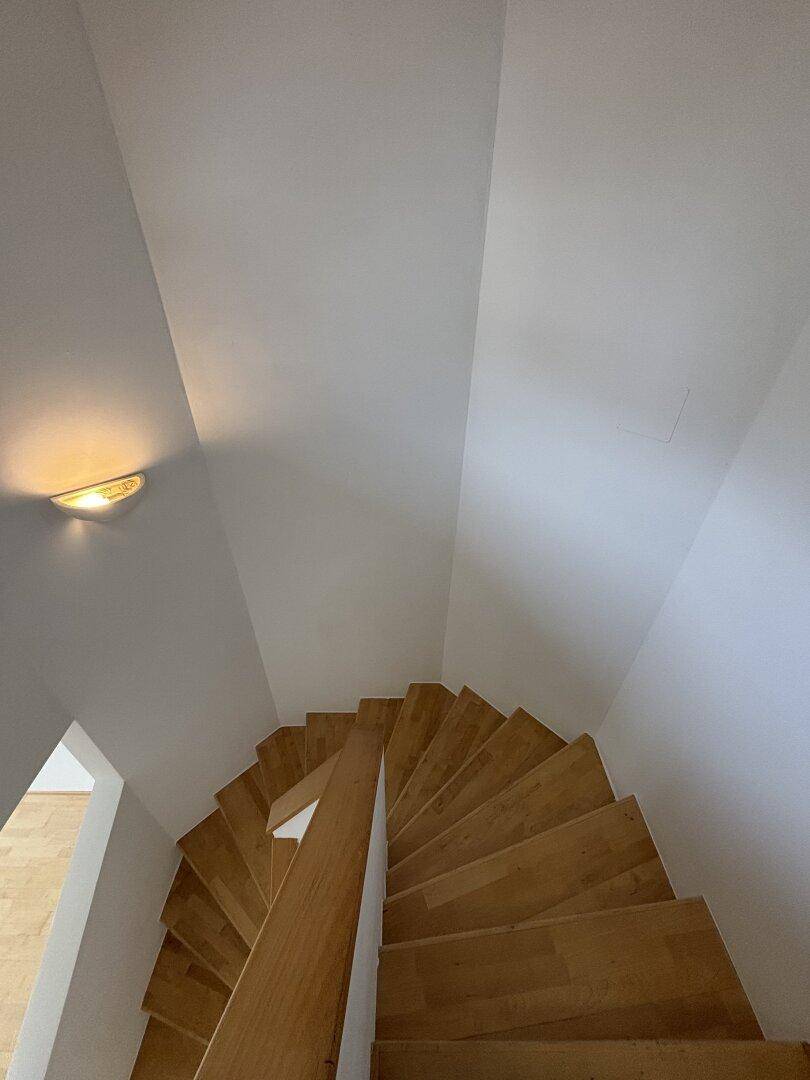 Holztreppe mit elegantem Geländer, die die verschiedenen Ebenen des Hauses miteinander verbindet.
