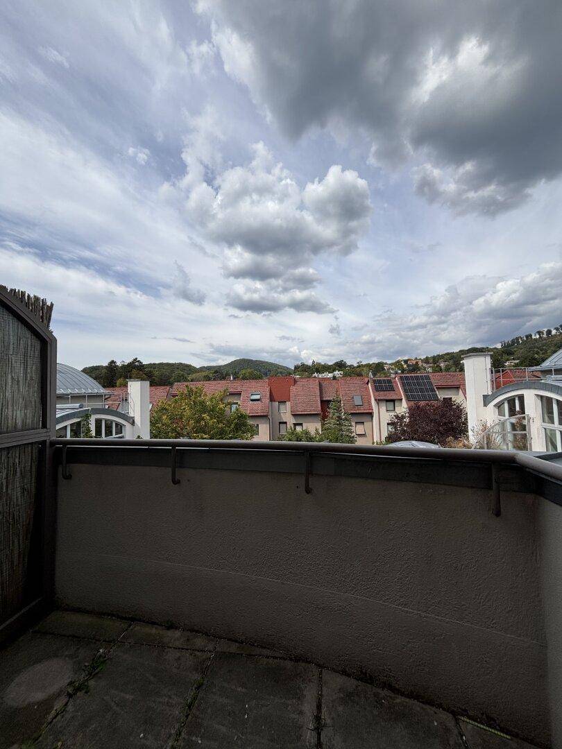 Dachterrasse mit weitem Blick über die Dächer der Stadt und die umliegende grüne Landschaft.