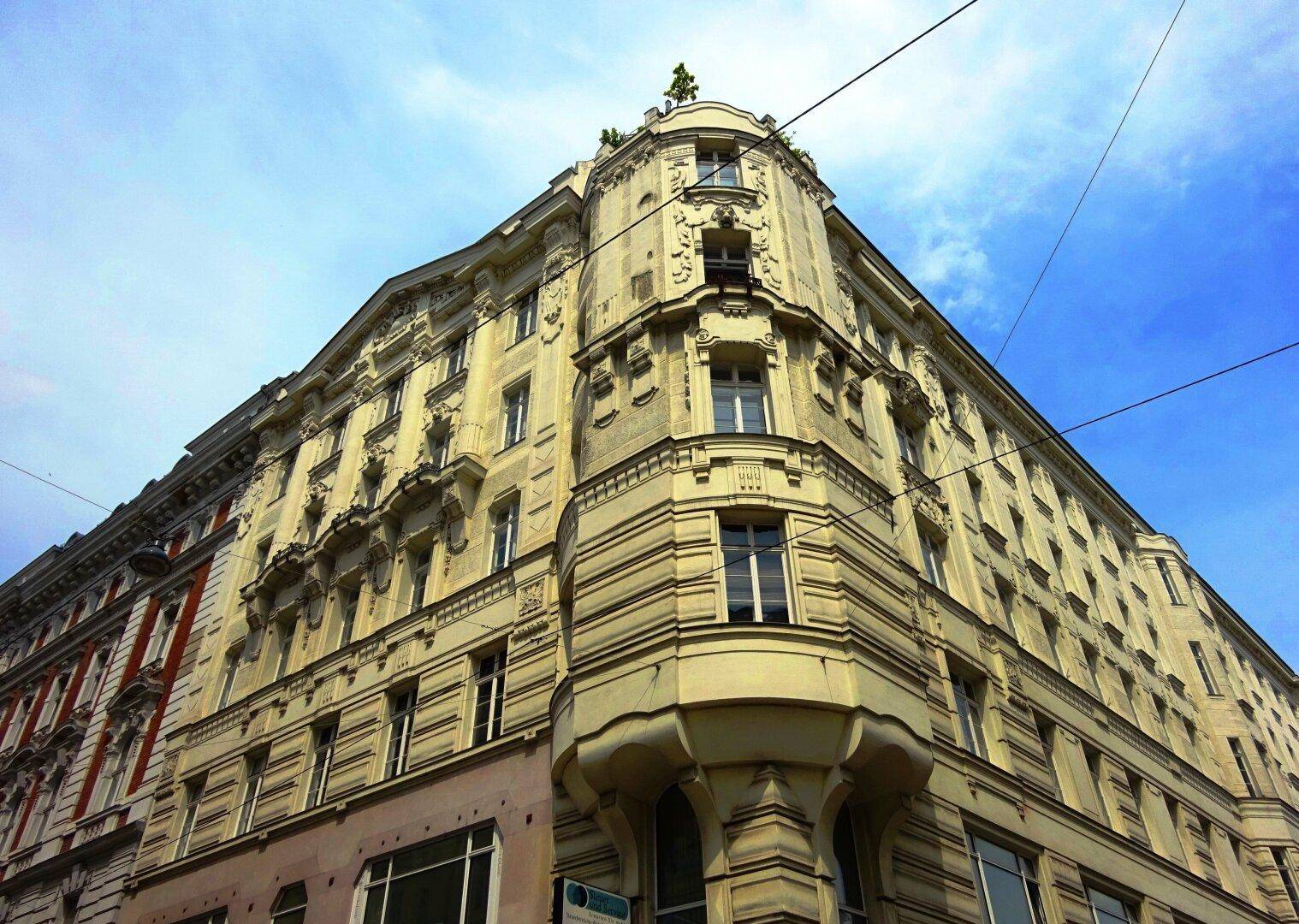 Eindrucksvolle Eckfassade eines historischen Gebäudes mit vielen Fenstern und architektonischen Details.