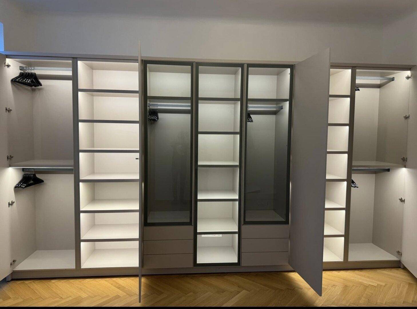 Große, beleuchtete Einbauschränke mit Glasfronten und viel Stauraum für Kleidung.