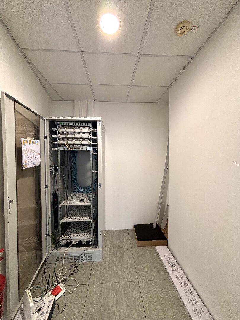 Serverraum mit offenem Serverschrank, Verkabelung und technischer Ausstattung für die IT-Infrastruktur.