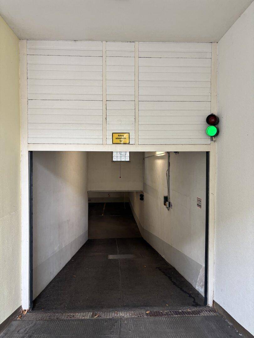 Einfahrt zu einer Tiefgarage mit Rampe und Ampelsystem für die Zufahrtskontrolle.