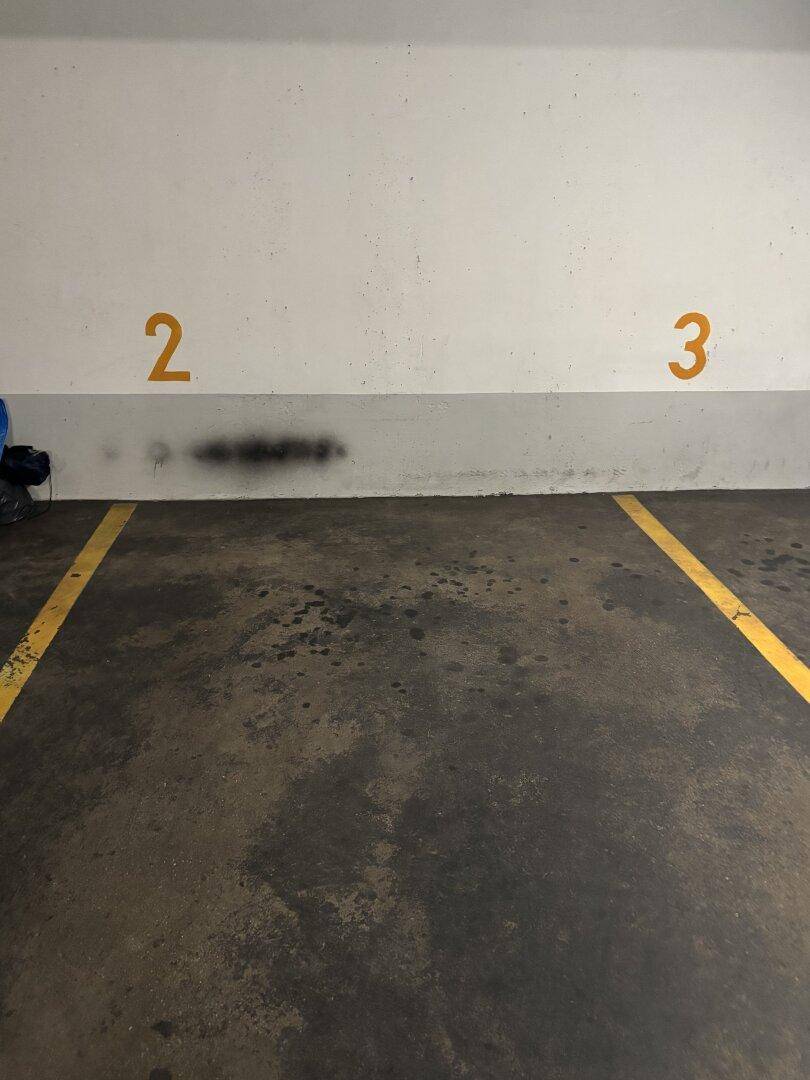 Parkplatz in einer Tiefgarage mit Markierungen und Nummern an der Wand.