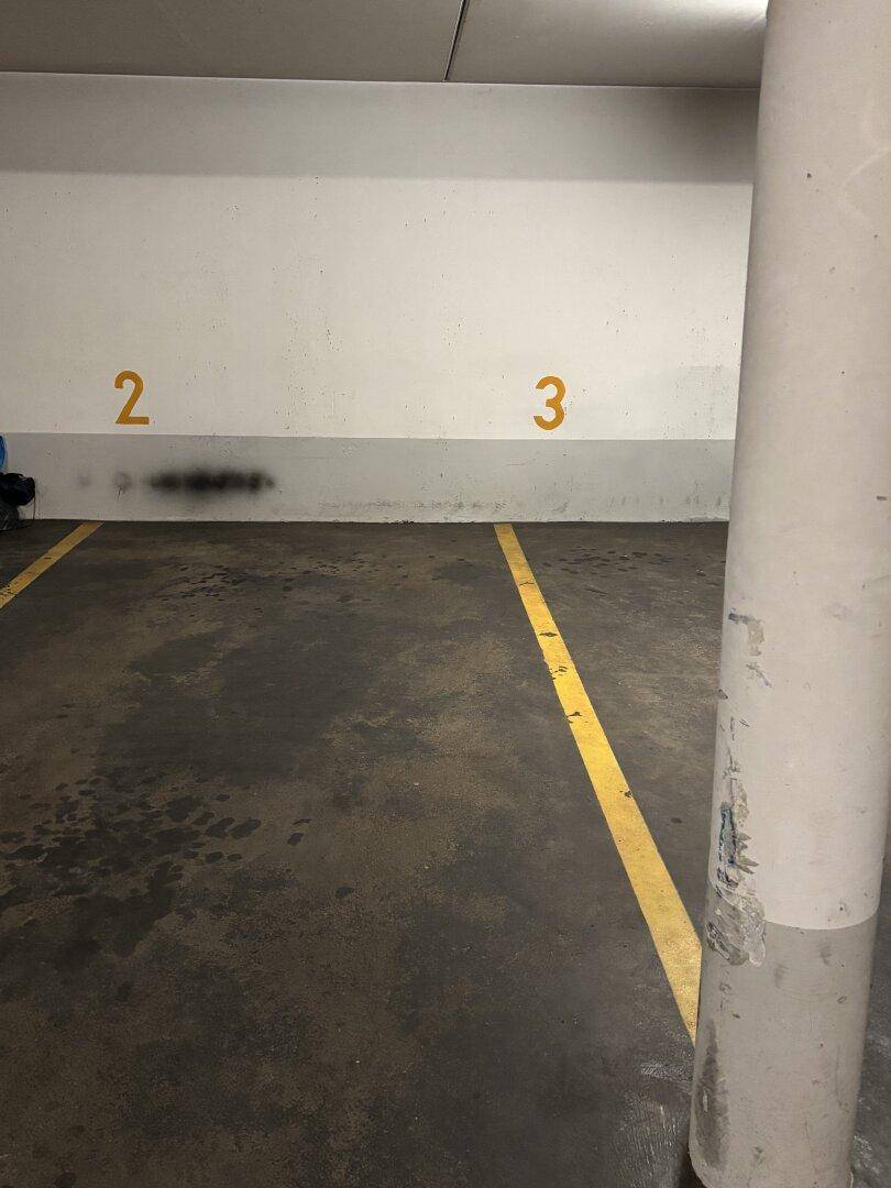 Tiefgaragenstellplatz mit Betonpfeiler und Wandmarkierungen für die Parkposition.