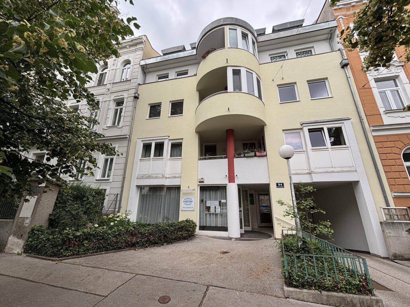 Moderne Gebäudefassade mit geschwungenen Balkonen und hellgelbem Anstrich.