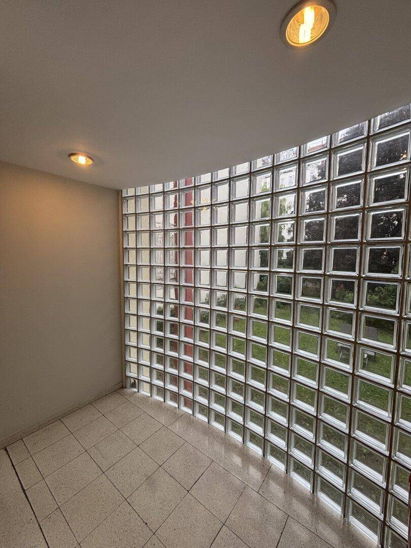 Innenraum mit großer Glasbausteinwand, die für natürliches Licht sorgt.