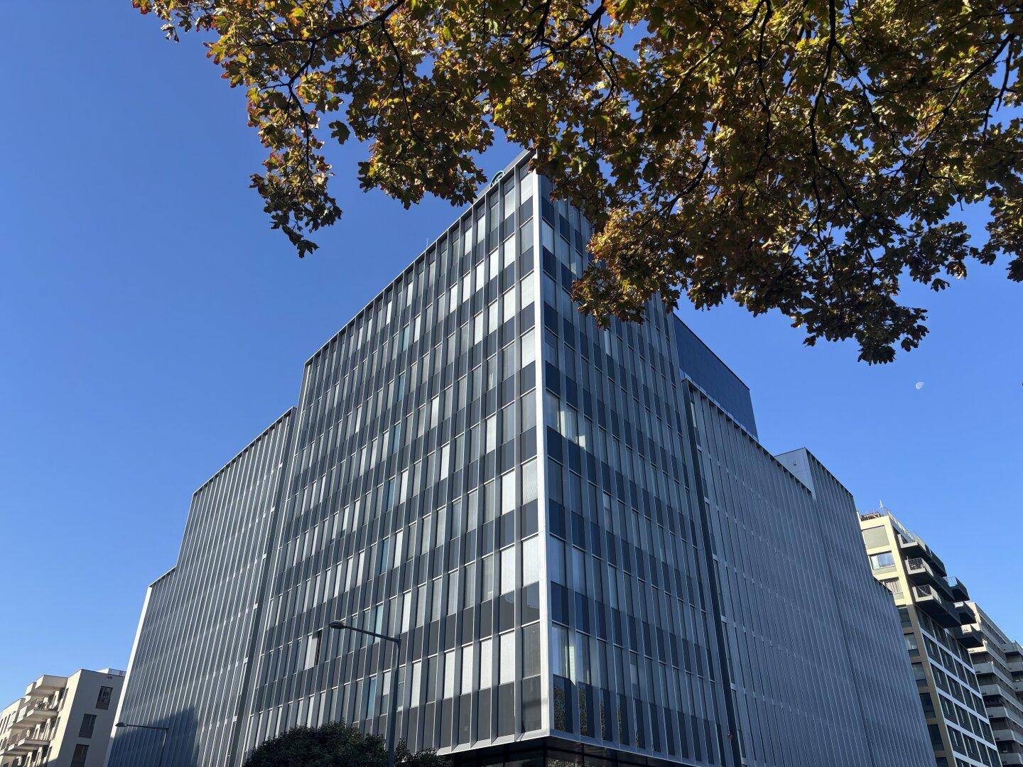 Modernes Bürogebäude mit markanter Glasfassade und klarem Himmel im Hintergrund.