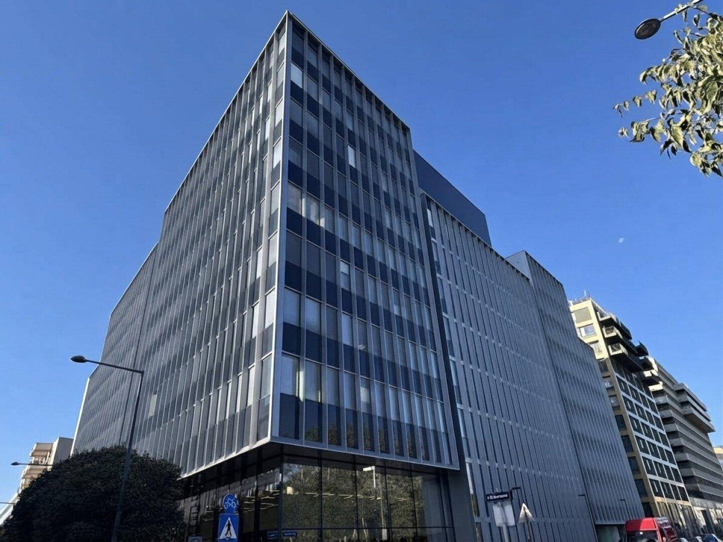 Modernes Bürogebäude mit markanter Fassade und großen Fensterfronten unter blauem Himmel.