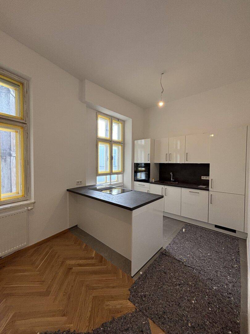 Neue Küche mit weißen Hochglanzfronten, Kochinsel und Parkettboden, derzeit in Renovierung.