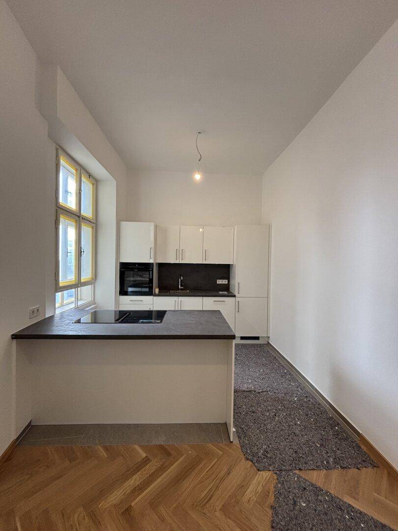 Moderne Küche mit weißen Schränken, Kochinsel und dunkler Arbeitsplatte, noch in Renovierung.