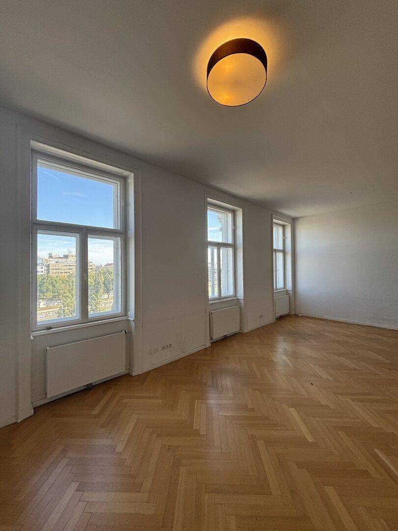 Geräumiges, unmöbliertes Wohnzimmer mit Fischgrätparkett und Stadtblick.