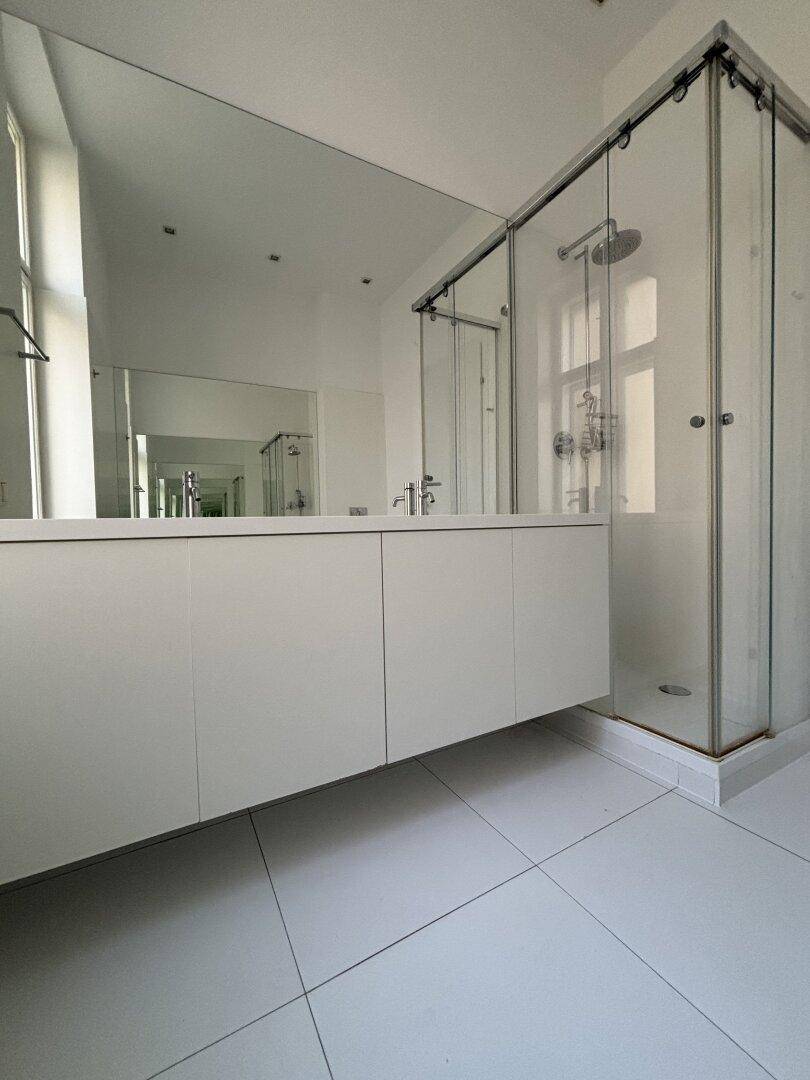Modernes Badezimmer mit großer Dusche, Doppelwaschbecken und Spiegelfläche.