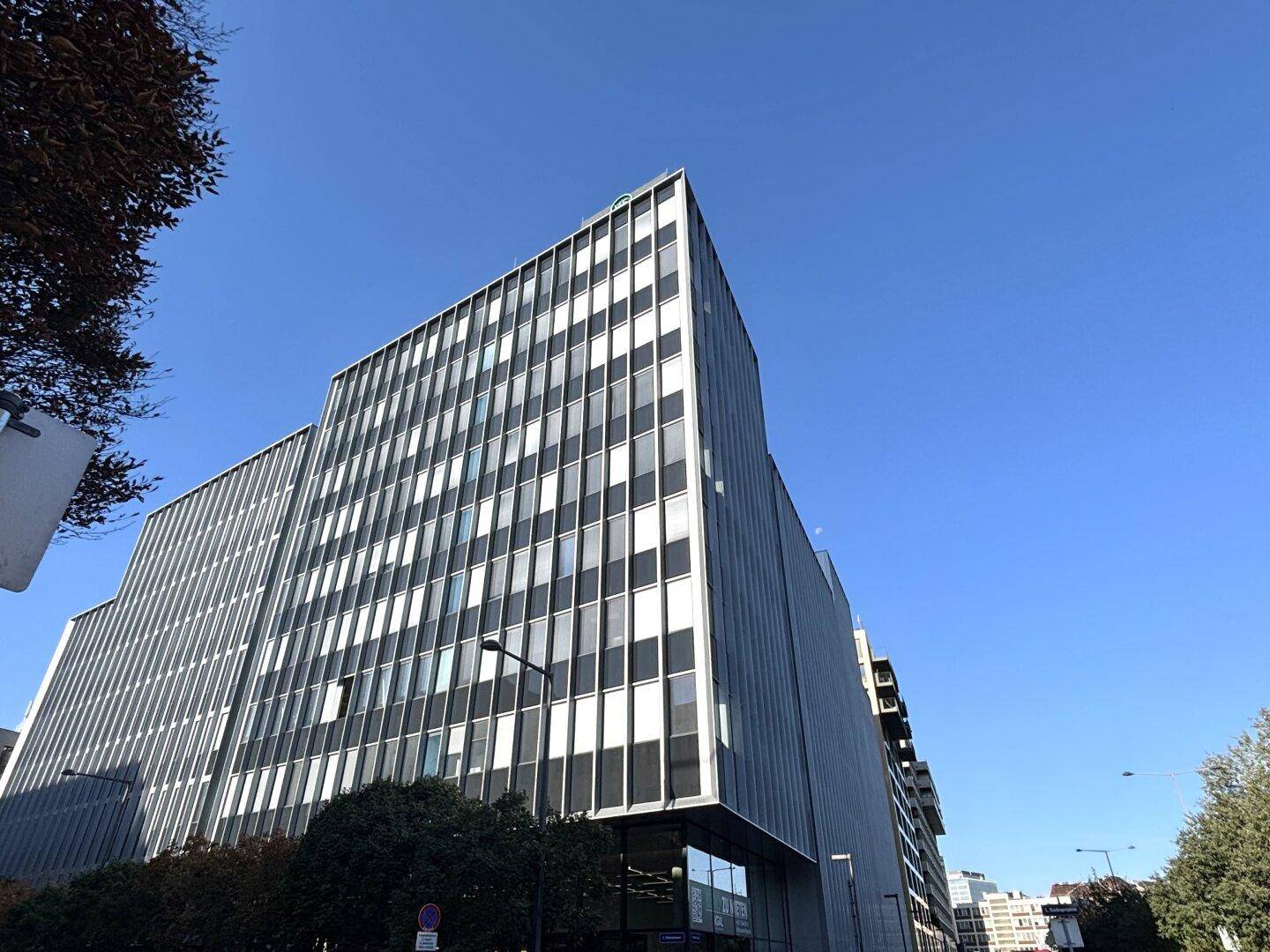 Zeitgenössisches Bürogebäude mit einer beeindruckenden Fassade und großen Fensterflächen an einem sonnigen Tag.