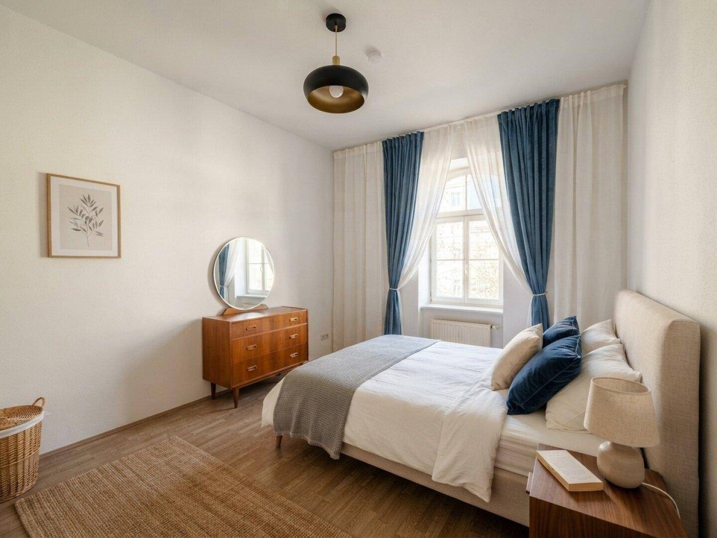 Gemütliches Schlafzimmer mit Holzboden, Doppelbett und blauen Vorhängen.