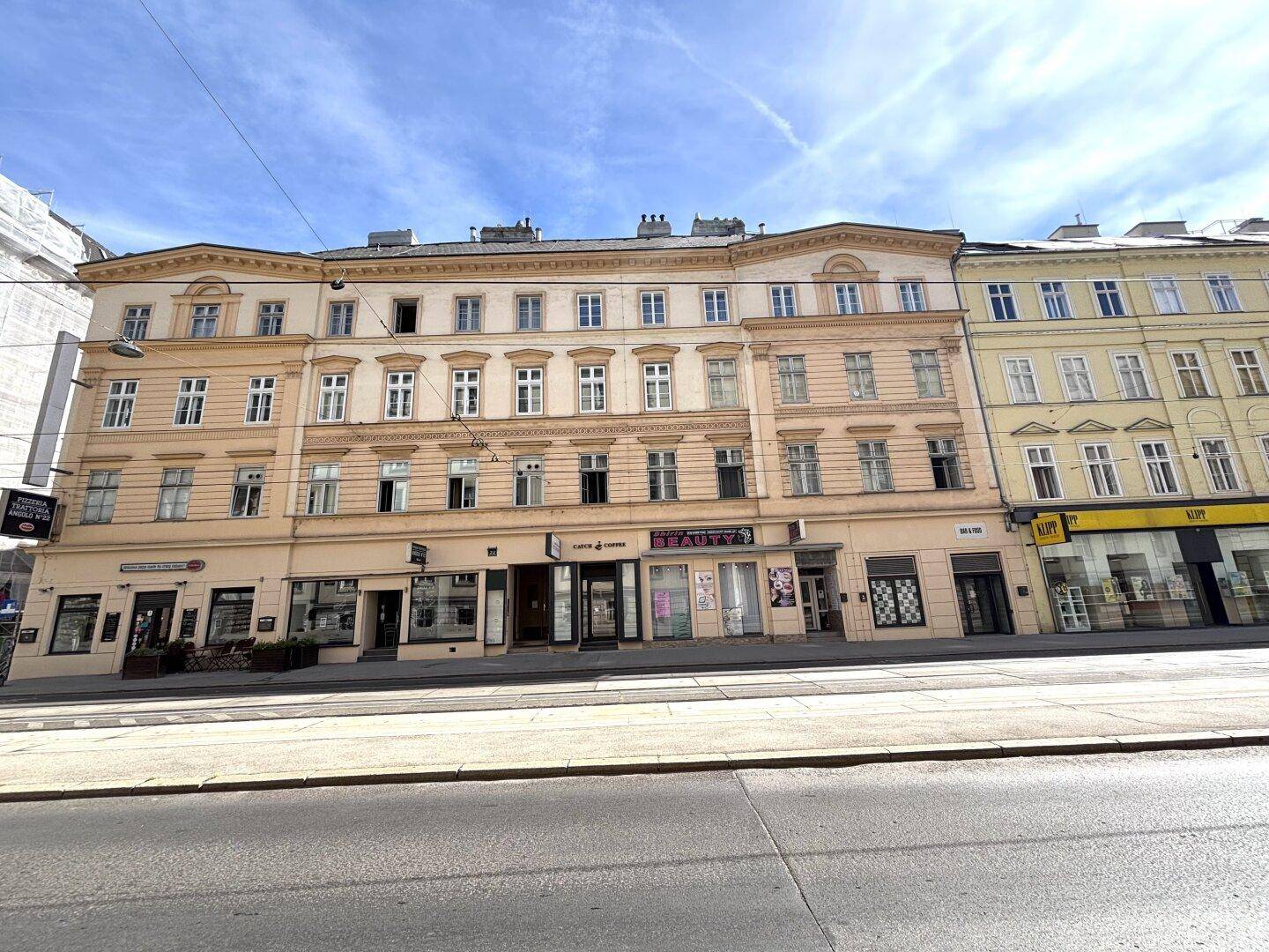 Historisches Gebäude mit mehreren Etagen, Geschäften im Erdgeschoss und klassischer Fassade.
