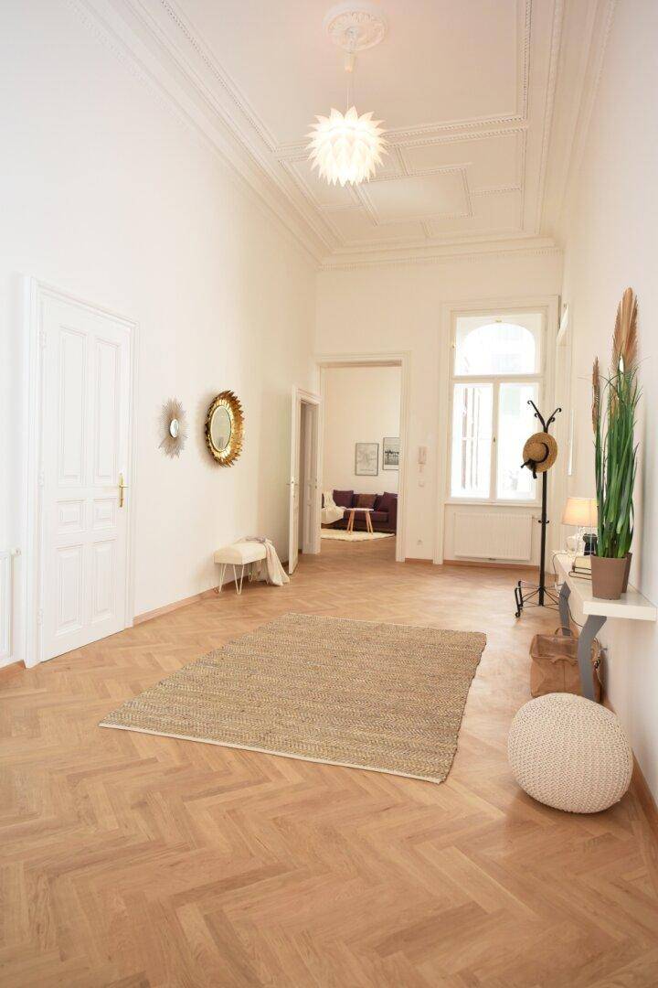 Geräumiger Flur mit Fischgrätparkett, hohen Decken und stilvoller Dekoration.