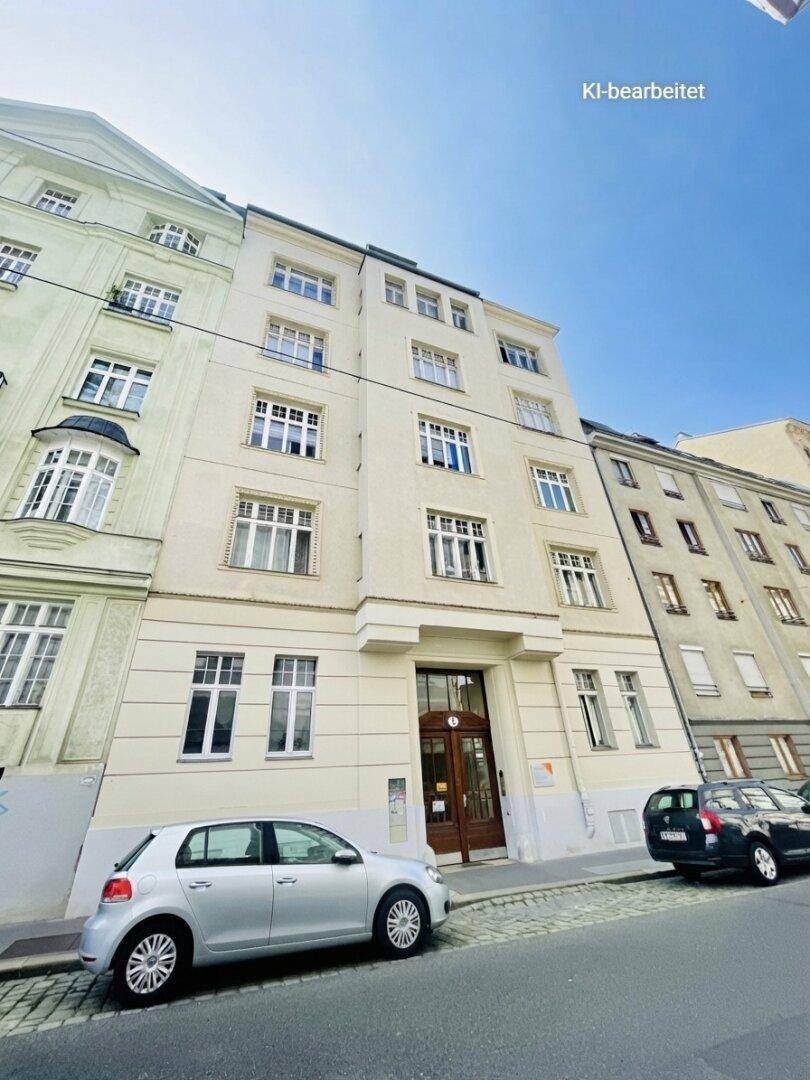 Klassische Fassade eines Mehrfamilienhauses in städtischer Umgebung mit großen Fenstern und Parkplätzen.