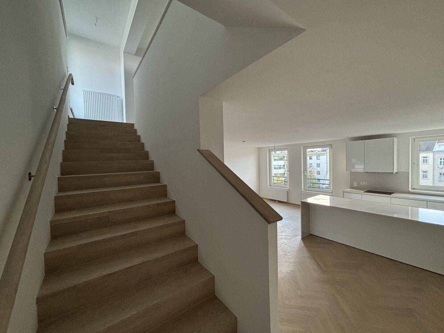 Moderne Holztreppe mit hellem Geländer, die zum oberen Wohnbereich führt.